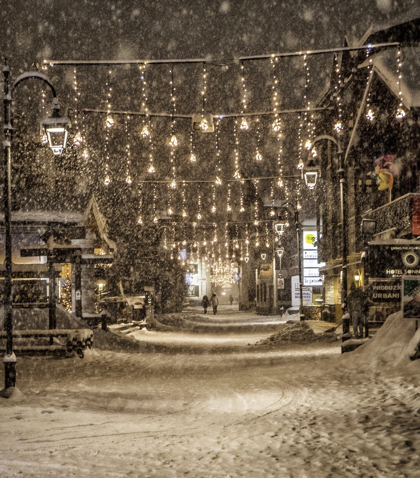 Via centrale di Livigno di notte durante una nevicata, con luci natalizie